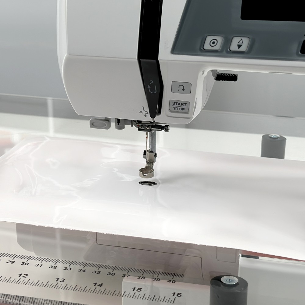 White low-friction surface of Queen Size Supreme Slider fitted around a sewing machine needle